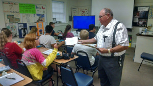 Mr. Sabbadino hands out a piece of paper to each of his students.