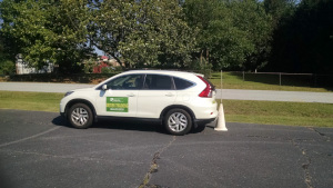 A driving student backs up until the rear bumper touches the cone.