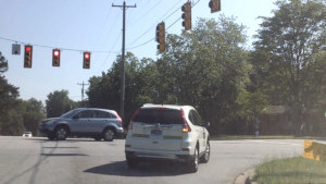 A driving student uses his blinker before making a right on red.